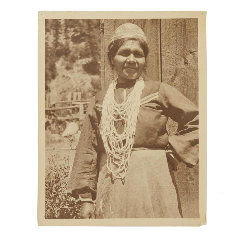 Grace Nicholson Photograph of Karok Indian Woman: Photograph of Karok woman (Indian Doctress) by Grace Nicholson. Handwritten in ink description verso. Stamped, verso, "Photo by Grace Nicholson, Pasadena, Cal." Dimensions: (overall) 11.37"h x 8.87"w.