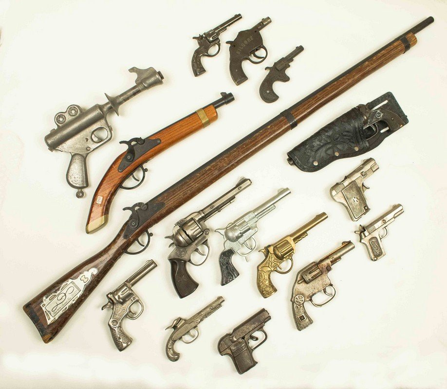 16 Assorted Cap Guns Including a Long Rifle: 16 Assorted Cap Guns, Including a Long Rifle. Cap guns are in cast iron, steel, wood and pot metal. Cap guns include Stevens "Model" Pistol, Kilgore "Border Patrol", Kenton "Kit Carson" and Daisy