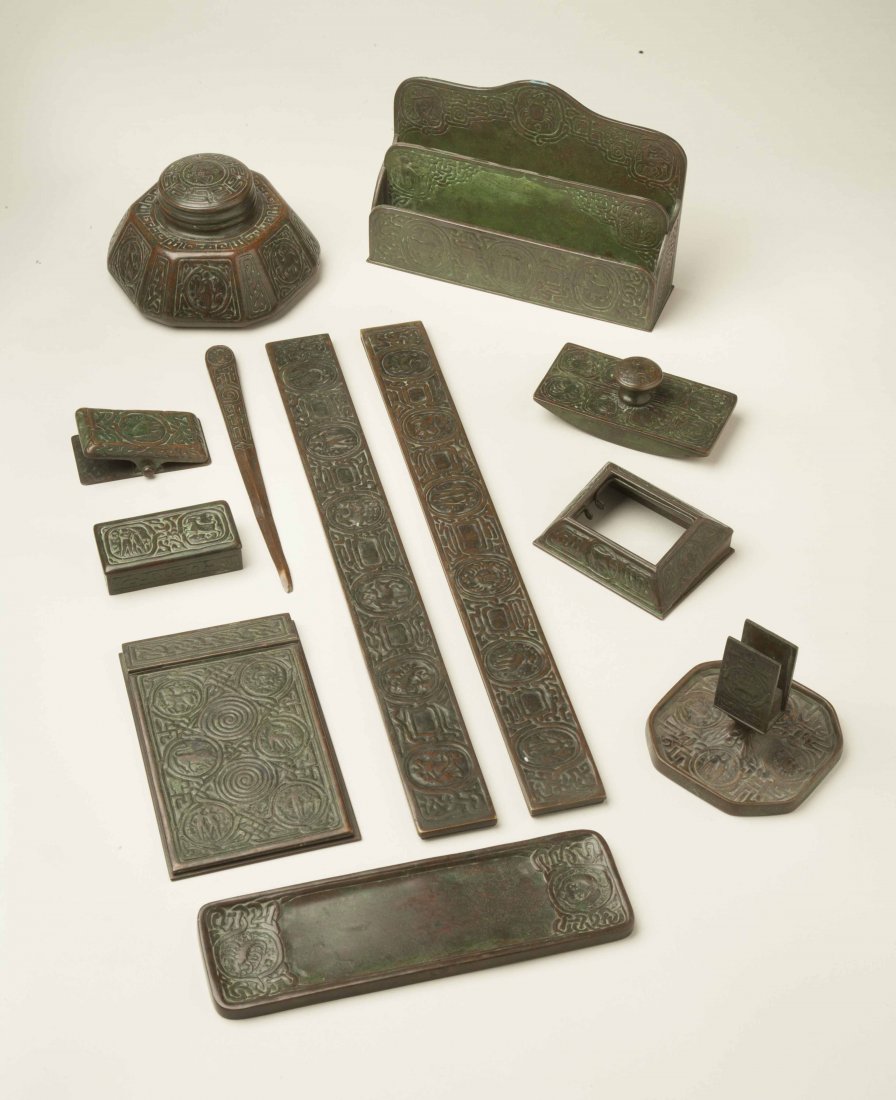 Tiffany Studios Zodiac Desk Set, 11 Piece: Eleven piece Tiffany bronze desk set in the Zodiac pattern, American, 20thc. Comprising a letter rack (1009), small box (802), notepad holder (1090), inkwell (1072), calendar base (no mark) (missing t