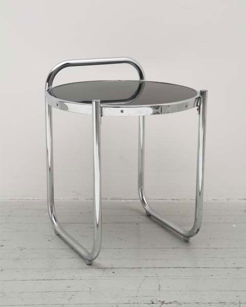 GILBERT ROHDE, 1884-1944: Table, model no. 13-C, ca. 1934 Chrome-plated tubular steel, black laminate, wood. Manufactured by Troy Sunshade, USA. 22 in. (55.9 cm) high, 18 ¼ in. (46.4 cm) diameter.