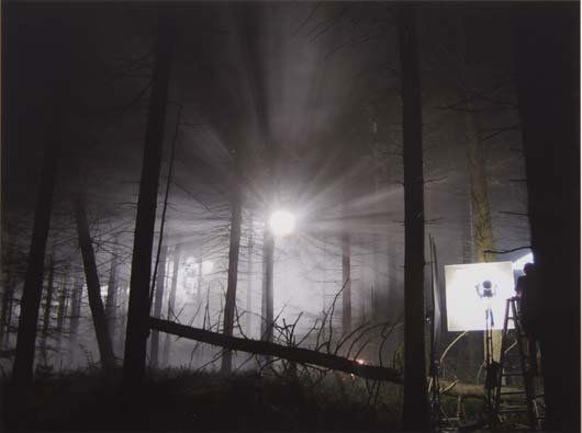 GREGORY CREWDSON, b. 1962: Production Still (Man in Woods #1, from Beneath the Roses), 2003 C-print. 12 x 16 in. (30.5 x 40.6 cm). Signed and dated lower edge.