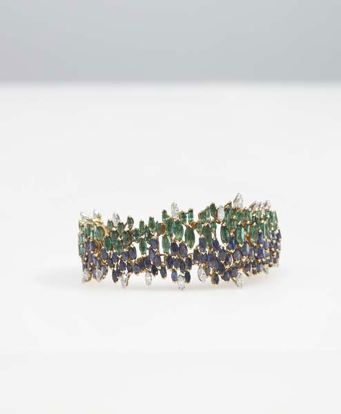 ANDREW GRIMA, b. 1921: Fine bracelet, 1960s 18 karat gold, sapphires, emeralds, diamonds. 6 ½ in. (16.5 cm) long, 1 ¼ in. (3.2 cm) wide. Clasp impressed with crown and twice with gold mark. Literature: Graham