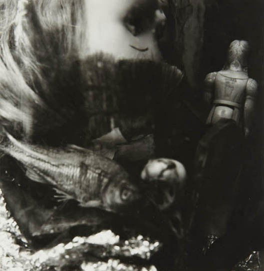RALPH EUGENE MEATYARD, Untiled (still life with dol: Untiled (still life with dolls and fish), 1959 Gelatin silver print. 6 3/4 x 6 5/8 in. (17.1 x 16.8 cm). Signed by Madelyn O. Meatyard in ink on the verso. PROVENANCE From the Estate of the Artist