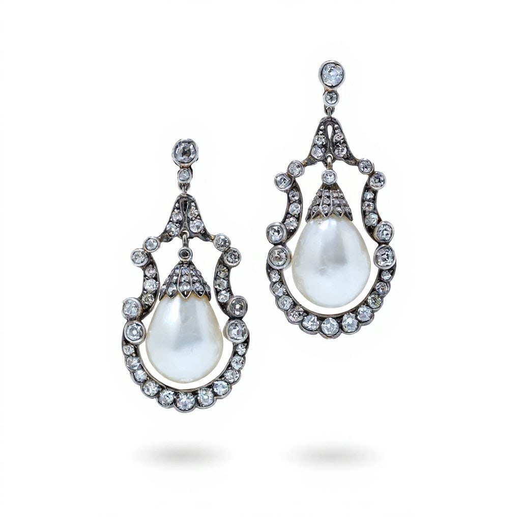 Victorian Natural Pearl and Diamond Drop Earrings: An elegant pair of Victorian drop earrings, crafted in 9ct gold with silver-topped settings, centred with exceptionally large natural saltwater pearls. Each pearl is suspended within an ornate diamond