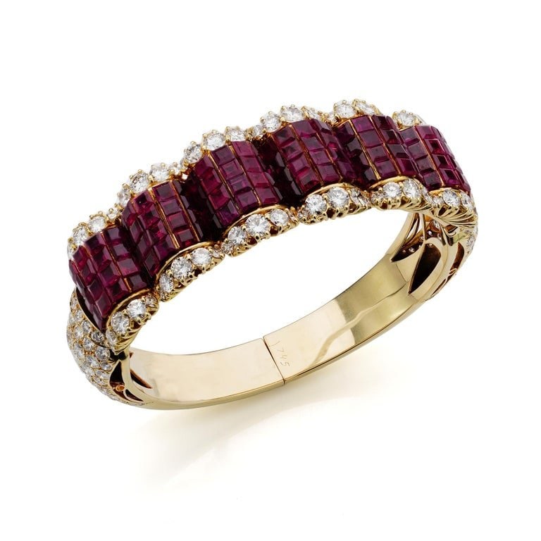 Simon Rudle 14KT gold ruby and diamond bangle: A bold and opulent 14kt yellow gold bangle, lavishly set with 120 square-cut rubies and 159 round brilliant-cut diamonds. T. Dimensions . Inner Diameter: 5.4 cm. Width: 2.1 cm. Weight: 81 g.