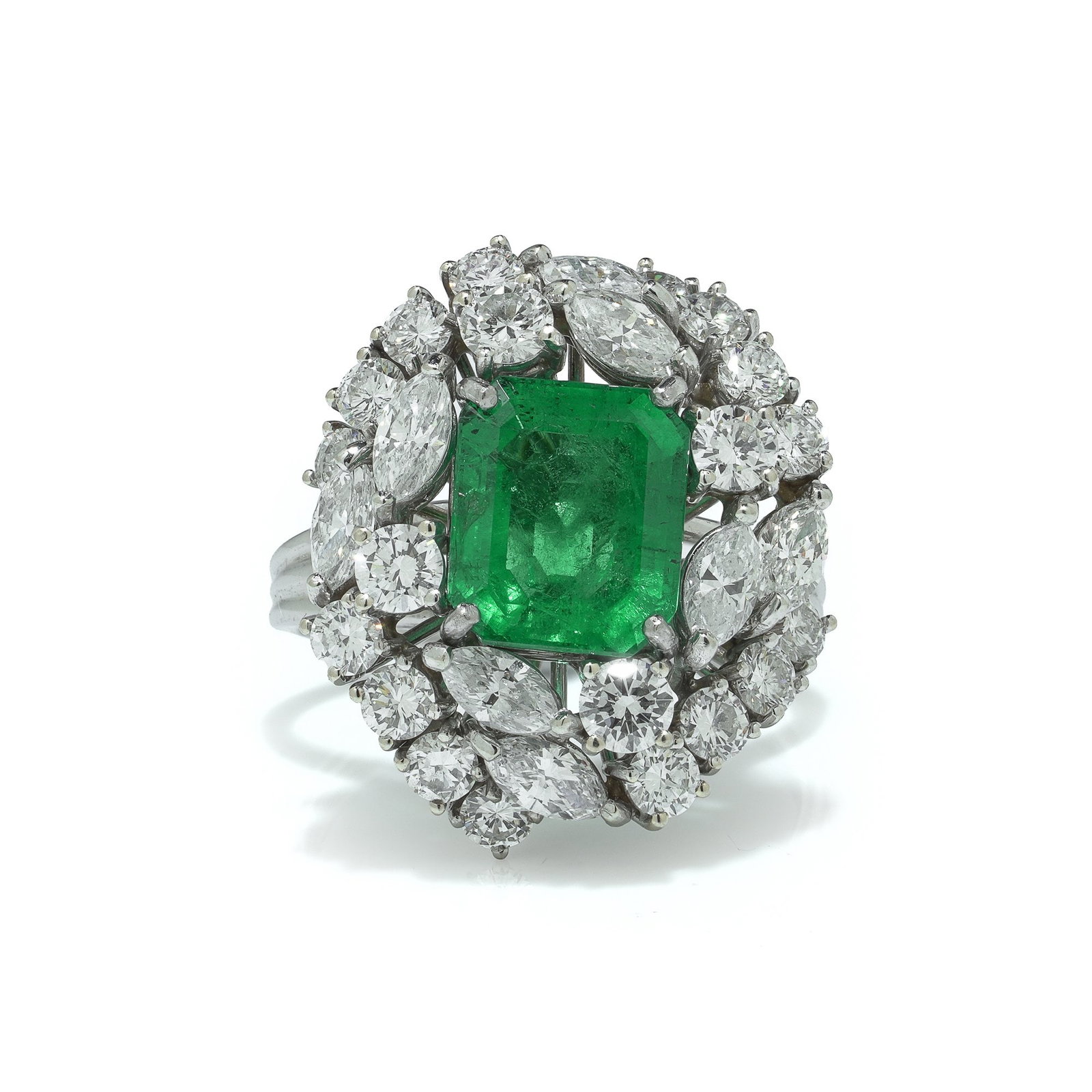 18KT White Gold 3.22ct Colombian Emerald Diamond Cluster Ring: An 18KT white gold cluster ring centred with a rectangular emerald cut Colombian emerald weighing 3.22 carats, framed by a substantial surround of round and marquise cut diamonds. The design is bold a