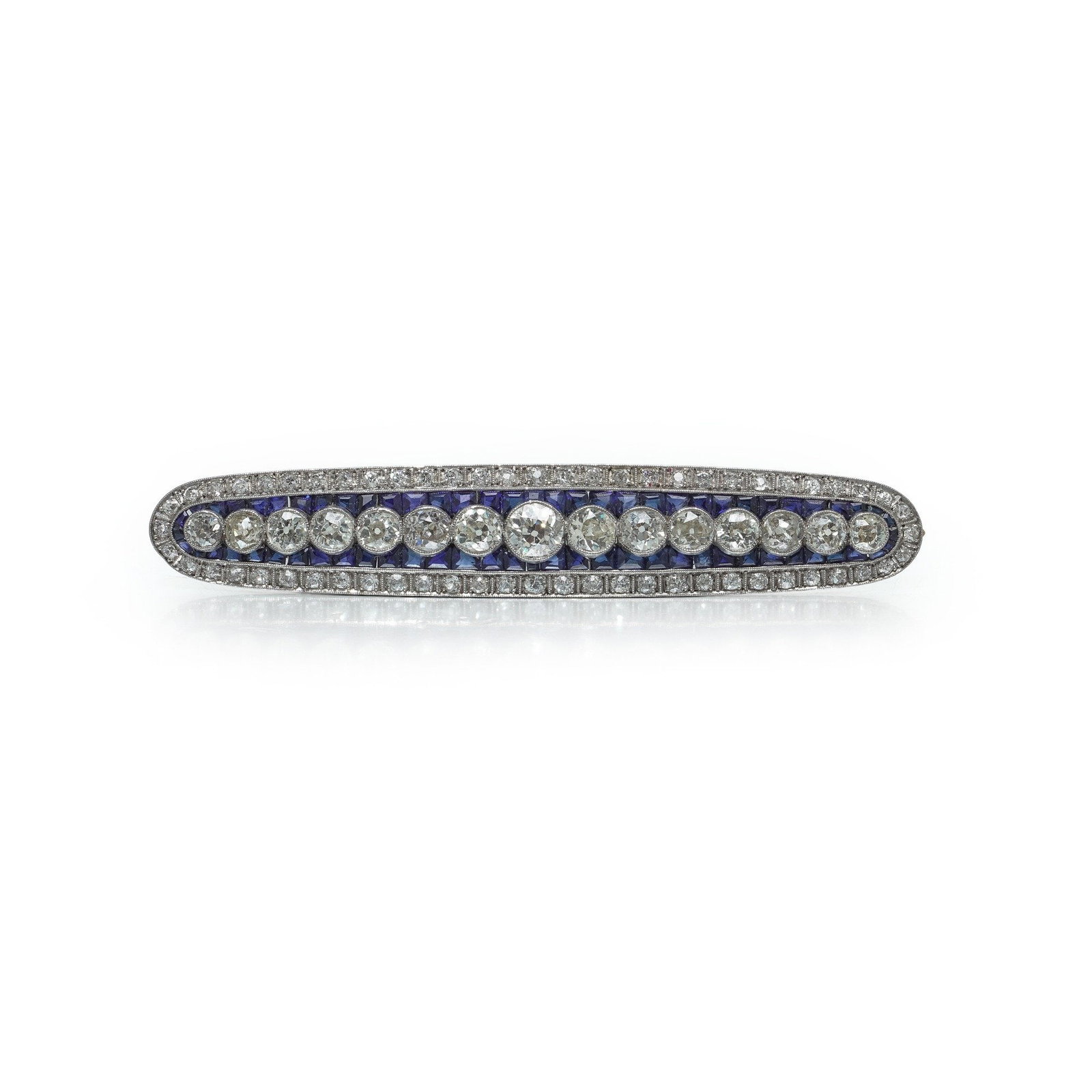 Art Deco Sapphire & Diamond Bar Brooch, Circa 1920s: An Art Deco sapphire and diamond bar brooch , circa 1920s, its long geometric bar lined with a graduated row of bright old-cut diamonds set against a channel of blue sapphires, with pave-set diamonds 