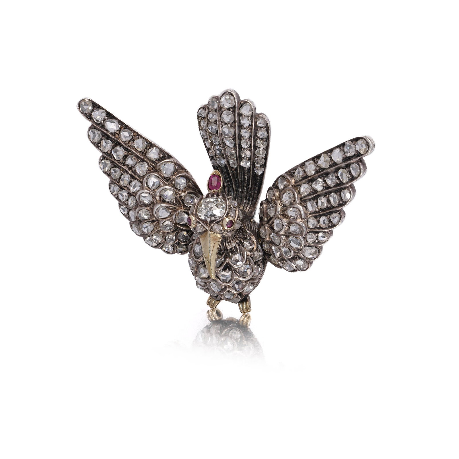Victorian 12KT Gold and Silver Bird Brooch with Rose Cut Diamonds and Ruby Eyes: Victorian bird-shaped brooch is finely crafted in 12kt gold and silver. The bird is captured mid-flight, with its wings and body pave-set with rose-cut and old mine-cut diamonds, complemented by ruby-