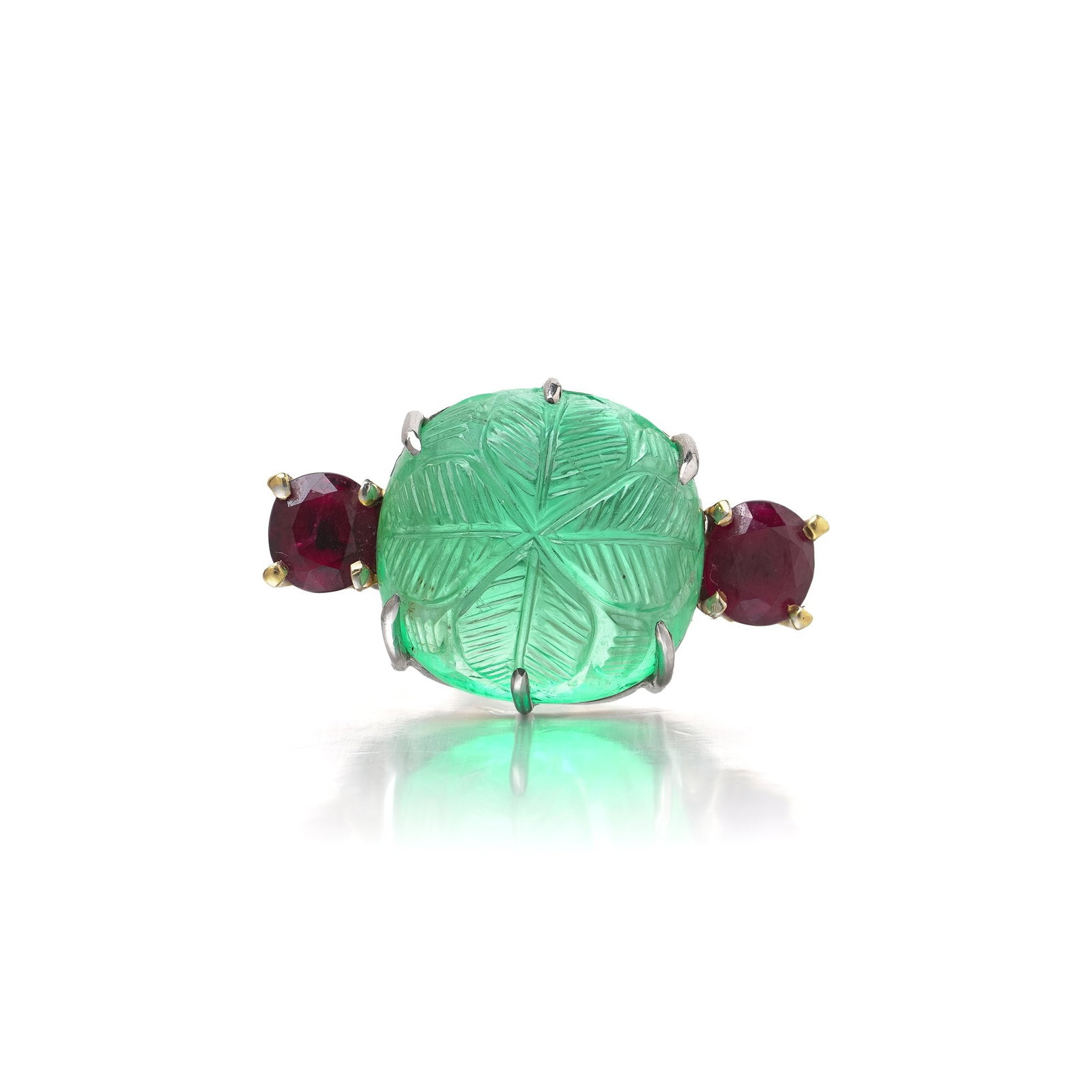 Vintage 18KT Gold Carved Emerald and Burma Ruby Ring: A striking vintage ring in 18KT yellow and white gold, centred on a substantial natural emerald carved with a floral motif and displaying a vivid green colour. The carved emerald is flanked by two rou
