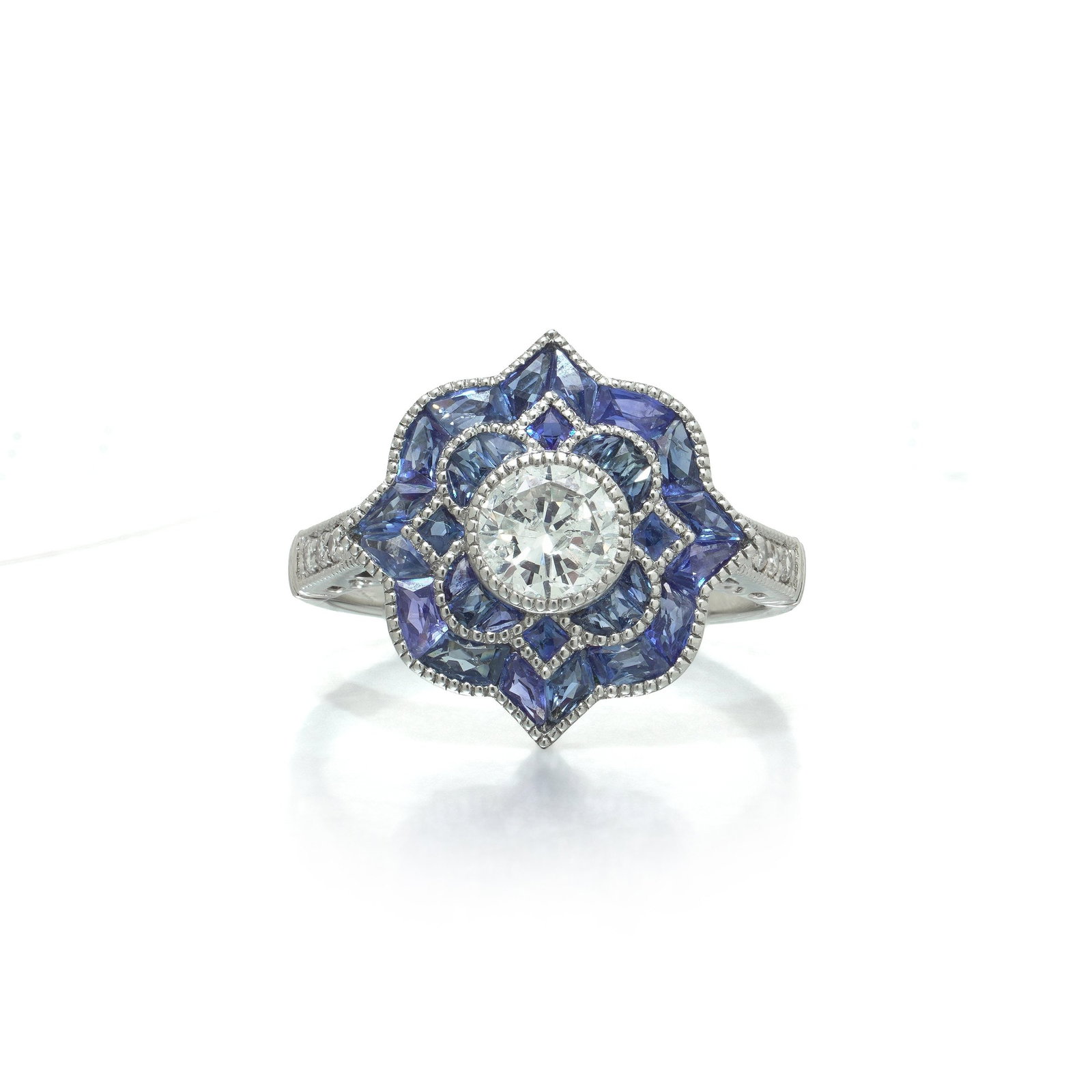 Art Deco Style Platinum Diamond and Calibre Sapphire Star Cluster Ring: Art Deco style platinum ring, the round brilliant cut diamond centre of 0.52 ct within a star of calibre cut sapphires. A round brilliant cut diamond of 0.52 ct is rub over set at the centre, and arou