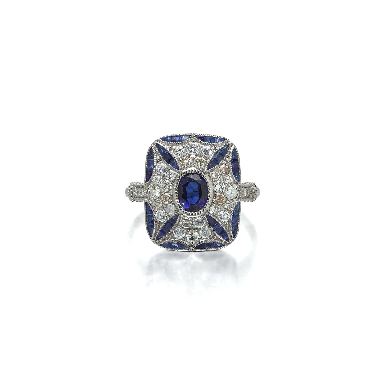Art Deco Style Platinum Sapphire and Diamond Cushion Plaque Ring, 0.66 ct Diamonds: Art Deco style platinum ring, the cushion shaped plaque set with an oval sapphire within a saltire of calibre cut sapphires and a diamond field. The plaque is cushion shaped with softly canted corners