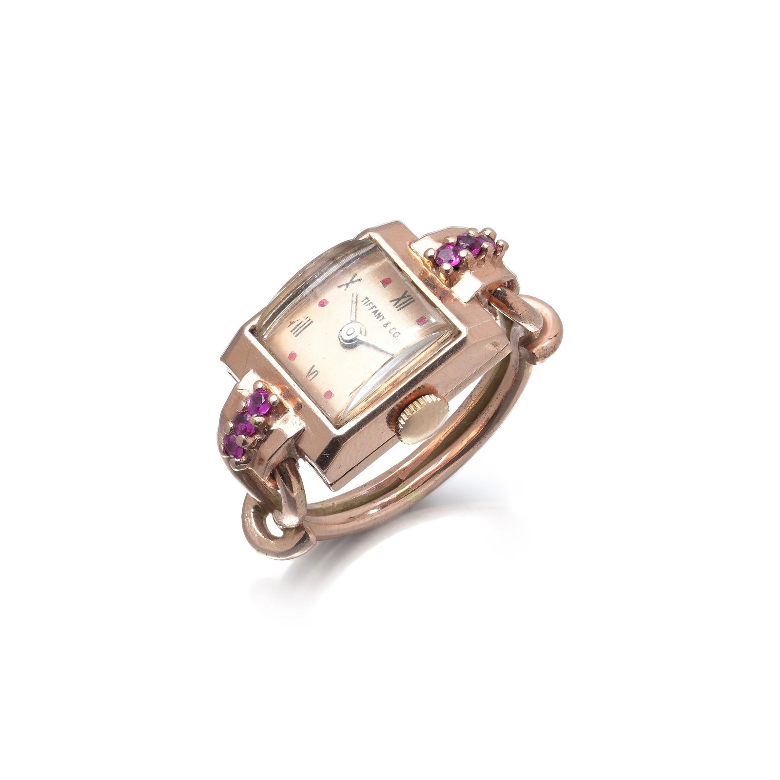 Tiffany & Co. 14KT Rose Gold Ruby Cocktail Ring Watch, Wyler Movement, Circa 1960s: Tiffany & Co. cocktail watch in 14KT rose gold, the rectangular dial signed Tiffany & Co. and flanked by a cluster of round rubies to each shoulder, on a hinged rose gold ring band. The case back is s