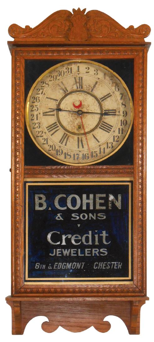 Clock, Gilbert Calendar Regulator w/adv from B. Cohen &: Clock, Gilbert Calendar Regulator w/adv from B. Cohen & Sons-Credit Jewelers, 8th & Edgmont-Chester, oak w/fancy pressed front, orig paper dial & reverse painted adv glass, VG cond, 36"H x 15.5"W.