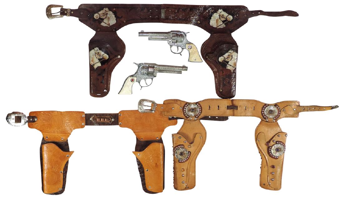 Toy cap guns & holsters (5), tooled leather double: Toy cap guns & holsters (5), tooled leather double holster w/horsehead design & Texan & Texan Jr. pistols w/steer head grips, Exc cond, tooled two-toned leather double holster w/silver studs & horsesh