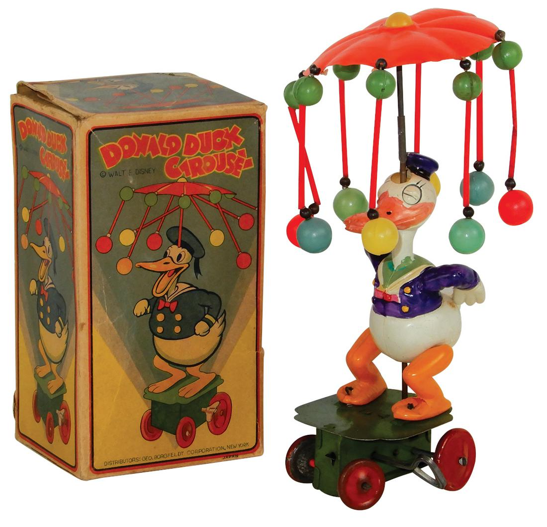 Toy Walt Disney Donald Duck Carousel, Made in Japan,: Toy Walt Disney Donald Duck Carousel, Made in Japan, box marked "Distributors Geo. Borgfeldt Corp. New York", celluloid on tin base windup, when wound umbrella spins as it moves in circles, crack acro