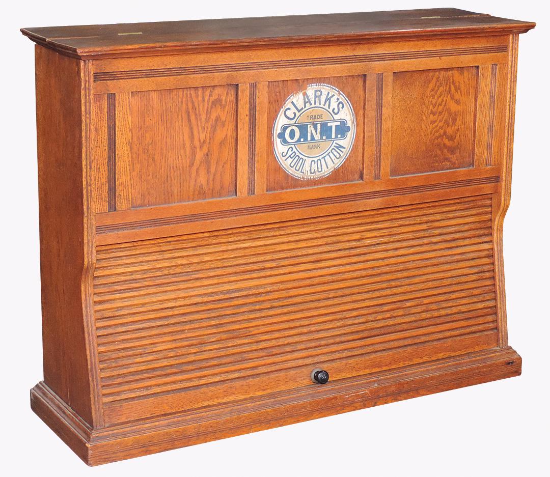 Country Store Spool Cabinet, Clark's roll front, oak: Country Store Spool Cabinet, Clark's roll front, oak w/tambour front that opens to multiple columns for spool thread, hinged top panel for restocking, nice large decal top center, VG to Exc cond w/ori