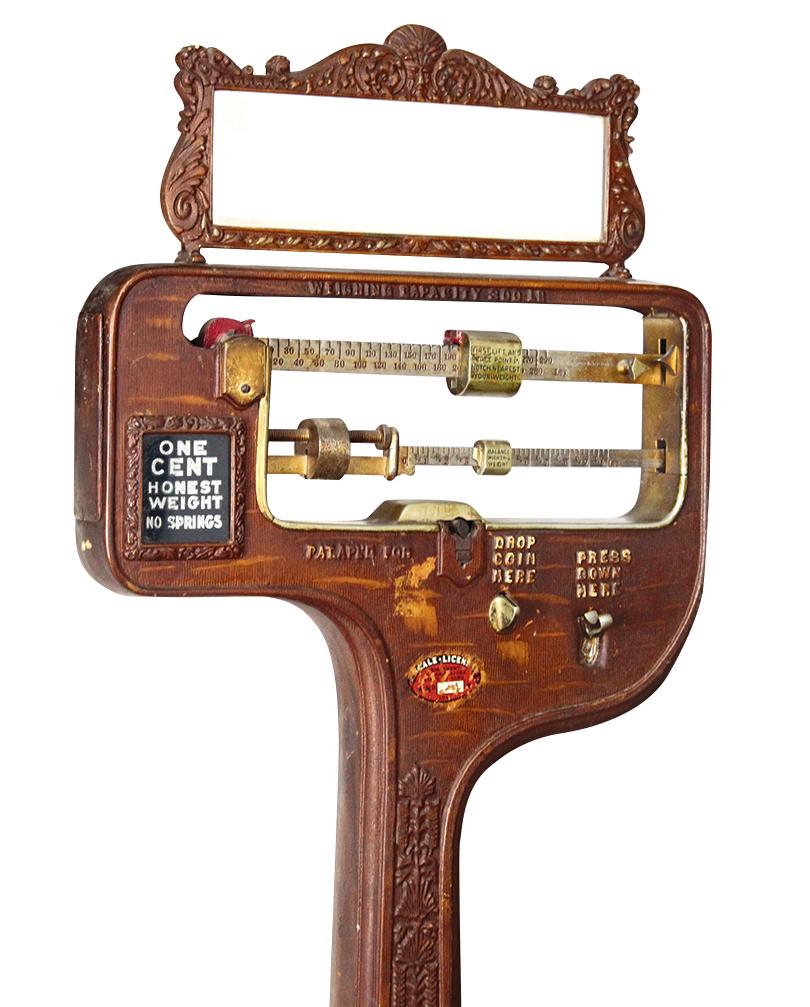Coin-Operated Honest Weight 1 Cent Scale, cast iron: Coin-Operated Honest Weight 1 Cent Scale, cast iron w/wood-grained finish, embossed foliates, scrolls & "Northwind" mask surmounting mirror frame, balance beam mechanism on a porcelain enameled base w