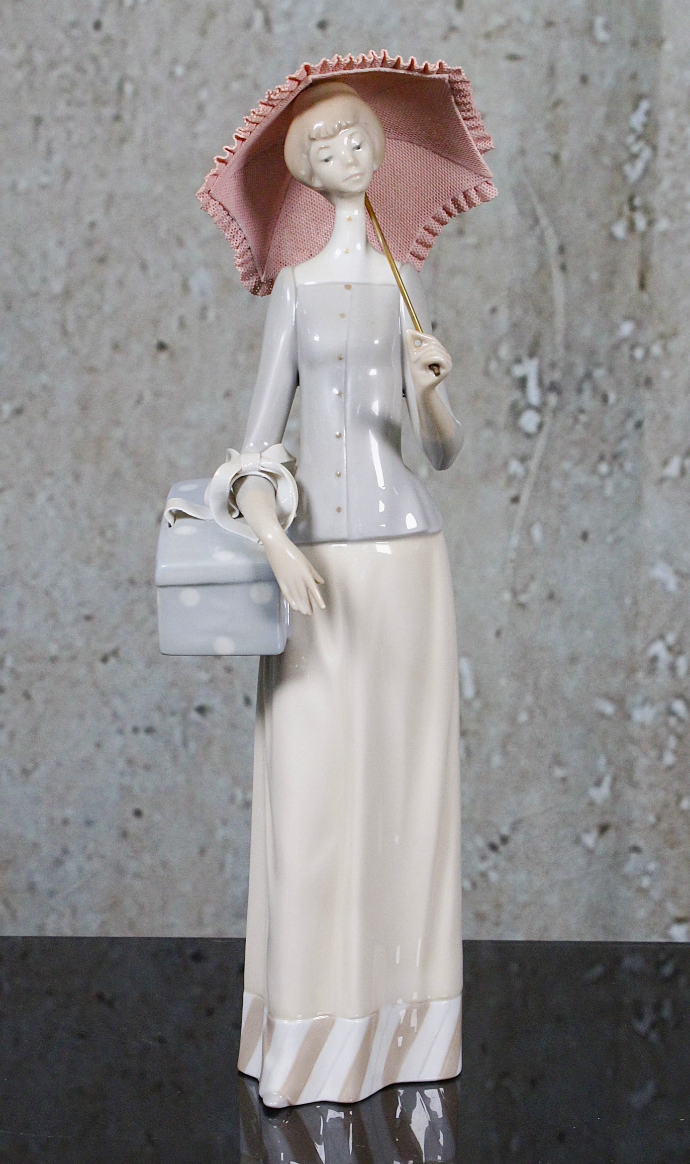 A Lladro Porcelain Figure "The Dress Maker": #4700 retired 1993, The figure in Exc cond, the umbrella with some losses to lace edge, includes original box, 14"H.