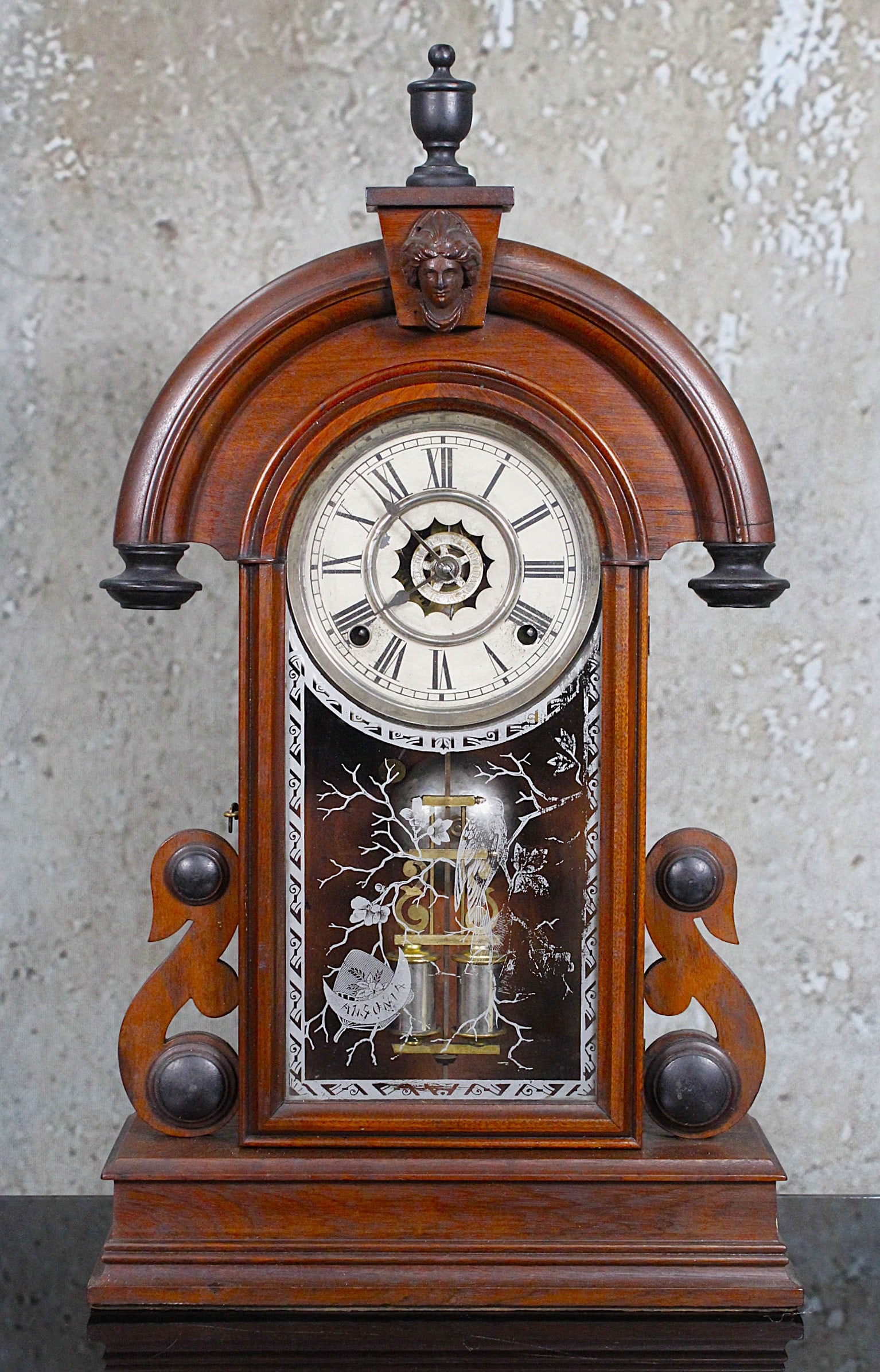 A Victorian Walnut Shelf Clock By Ansonia: Late 19th century with silvered dial, hour strike & alarm, original reverse painted glass, VG+ working cond and original finish, 23"H.