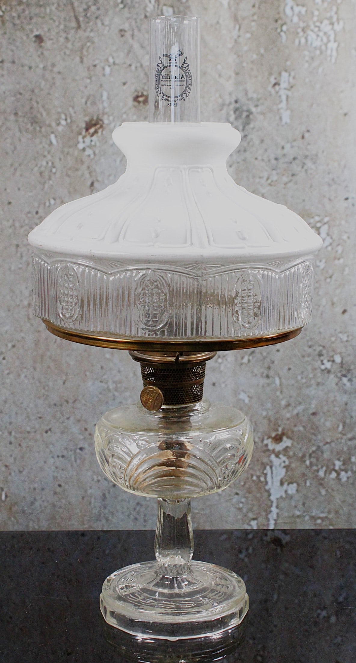 An Aladdin Washington Drape Oil Lamp: Clear pressed glass with white enameled shade, working burned and Aladdin chimney, Exc cond. 24"H total.
