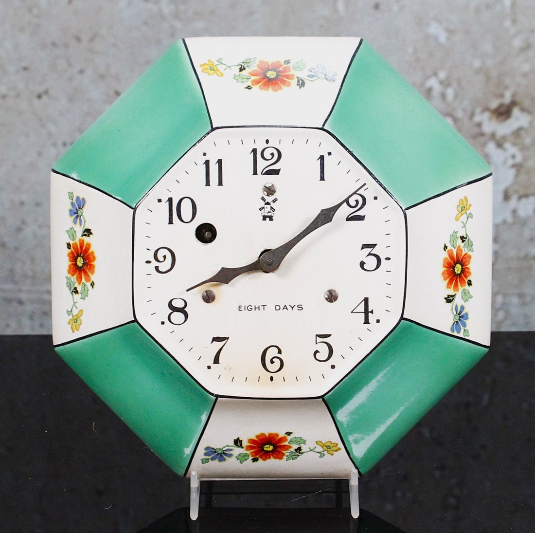 An Irving Miller Art Deco Kitchen Clock: Floral decorated paneled porcelain face w/8 day movement, VG working cond. 9"W.