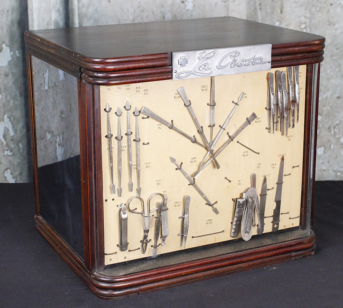 A Beauty Supply Store Display Case For LaCross: Circa 1950 wood with curved glass front with manicure tool samples opening to reveal 4 drawers with compartments, smoked mirrored panels at each end. 12"H x 14"W x 10"D. VG+ cond.