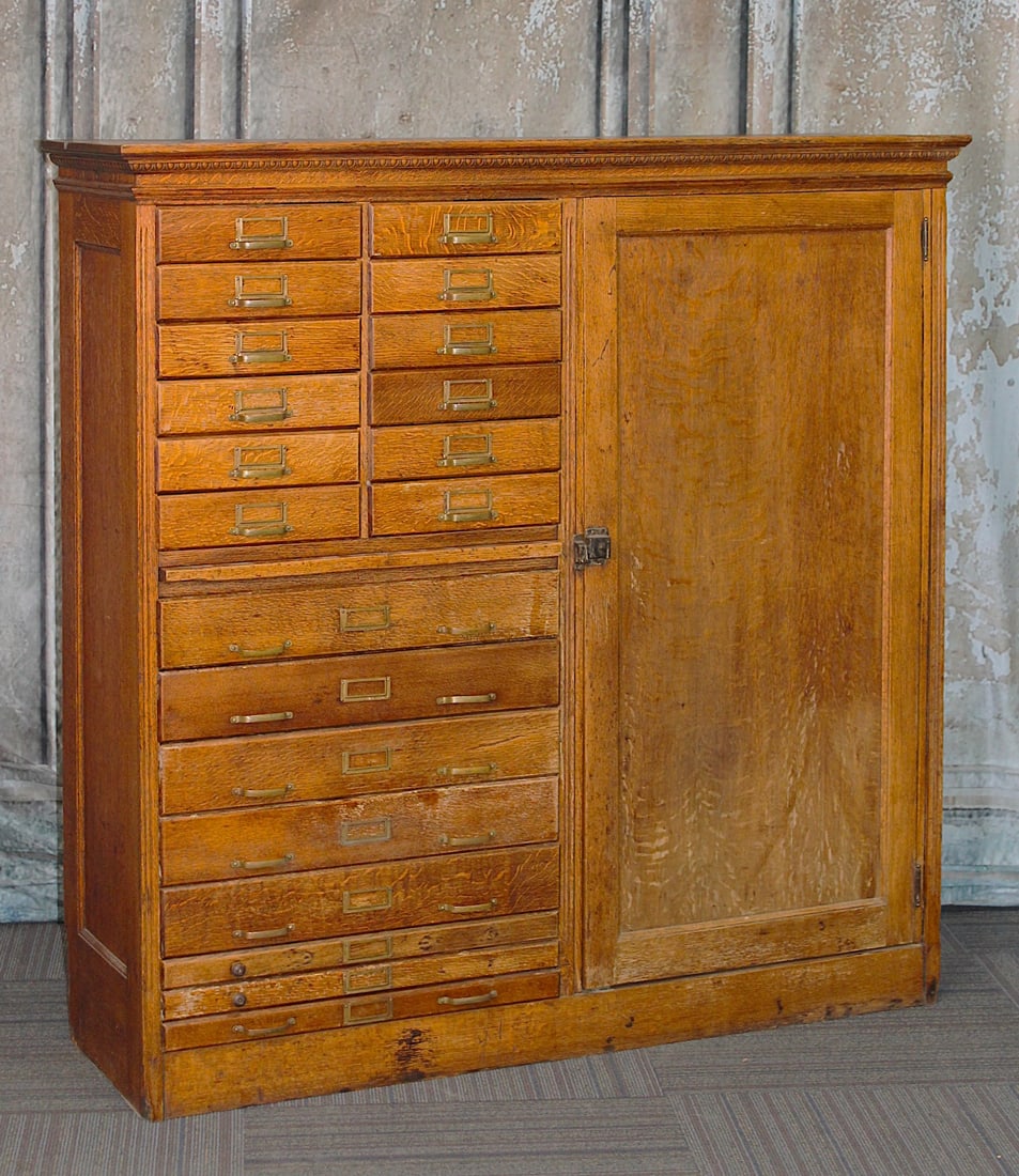 A Victorian 20 Drawer Oak Apothecary Cabinet: Paneled case with egg & dart cornice above 20 drawers, pull out tray and side locker with shelves, G+ original finish & condition noting drawer dividers and 4 pulls absent and some material loss to bo