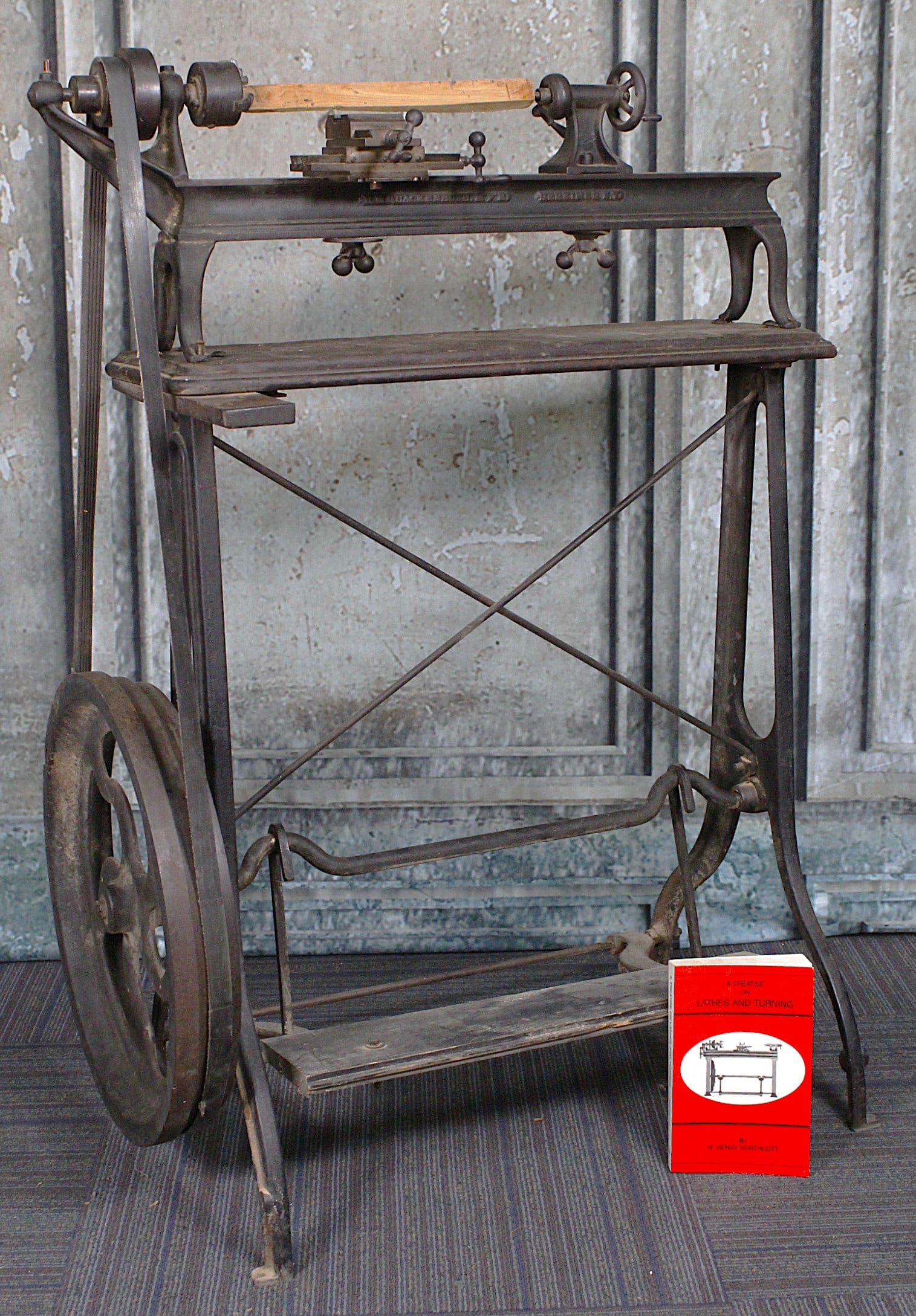 A Quackenbush Treadle Gunsmith Lathe: Foot operated, cast iron 6 inch lathe, appears mostly complete and likely operational with adjustments, G+ cond noting and early professional repair to one leg. 44"H x 31"W.