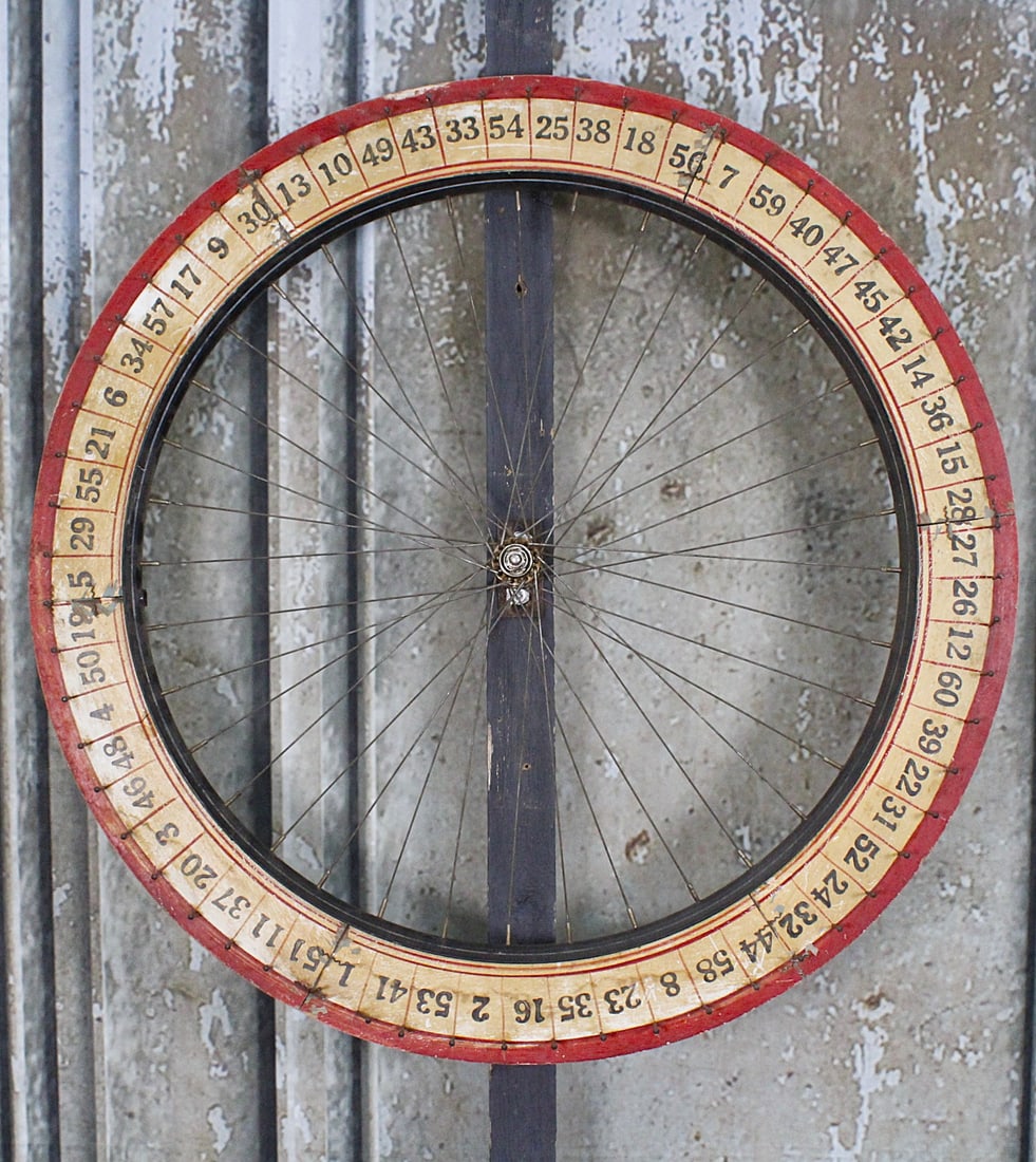 An Arcade Gaming Wheel: 1st half 20th century with painted wood numbers on spoked steel bicycle rim. G+ cond, 32"Dia & 74"L w/support.