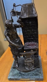 Bronze sculpture sculpture on a marble base of a blacksmith swinging a hammer at a piece of metal on