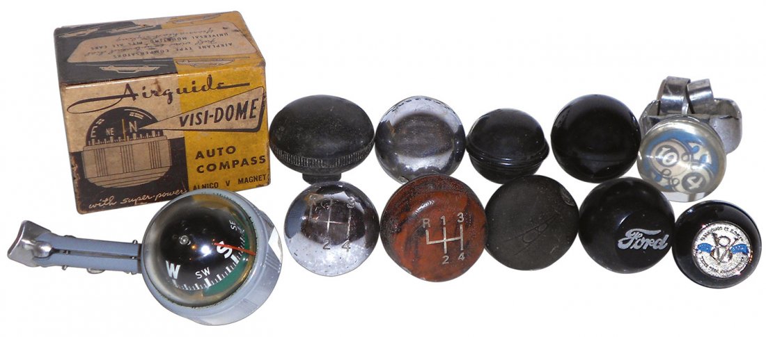 Automotive compass, steering wheel & shifter knobs: Automotive compass, steering wheel & shifter knobs (11), metal, rubber & plastic shifter knobs (9), one w/Ford on face, some w/out inserts; plastic steering wheel knob w/"10/4" on face & Air Guide Vis