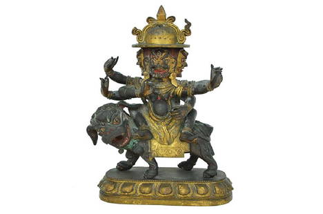 A TIBETAN PARCEL GILT BRONZE FIGURE OF A BUDDHIST DEITY: 20th century The three headed six-armed deity seated aback a mythological lion Traces of pigment 19 cm high