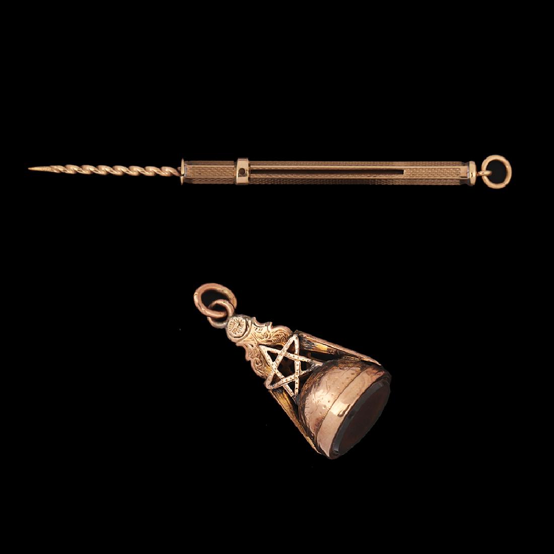 A LOT COMPOSED OF 2 9K GOLD PENDANTS:: A) a 9K rose gold pendant, in the form of a seal, set with a carnelian stone, decorated with a Star of David. B) A 9K gold decorated pendant (probably a mechanical pencil).