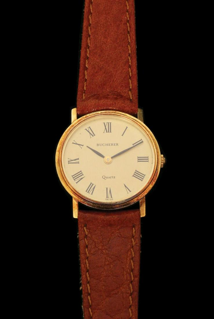 BUCHERER A 18K GOLD WATCH: Quartz mechanism, diameter approx. 24 mm. Brown leather strap and gold buckle.