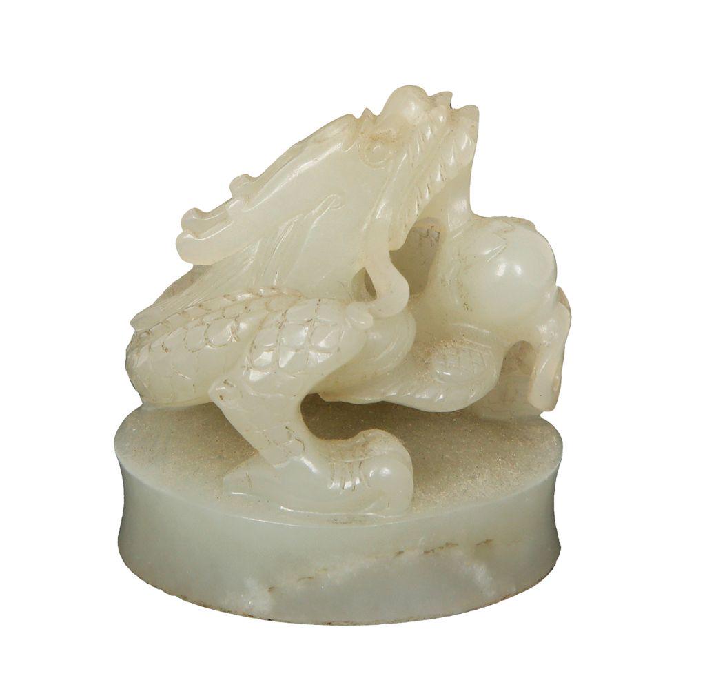 A CELADON JADE CARVING IN THE FORM OF A DRAGON: 19th century. 4 cm high. (minor chip)