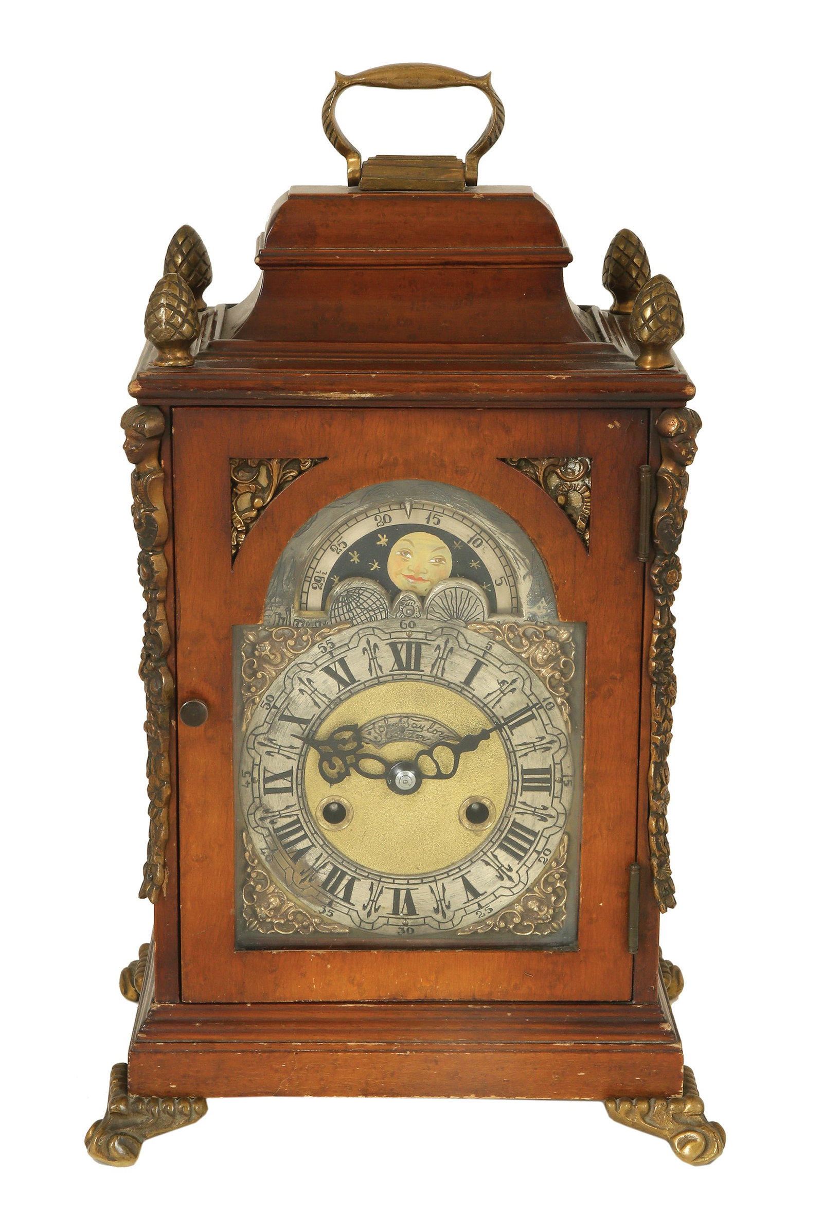 BRITISH OLD MANTEL CLOCK: Partially engraved wooden body in dark patina with heads, flowers and pine cones. Roman dial with moon phase disk and manufacturer's name JOHN TAYLOR. Strikes every half and full hour. Height: 44 cm.
