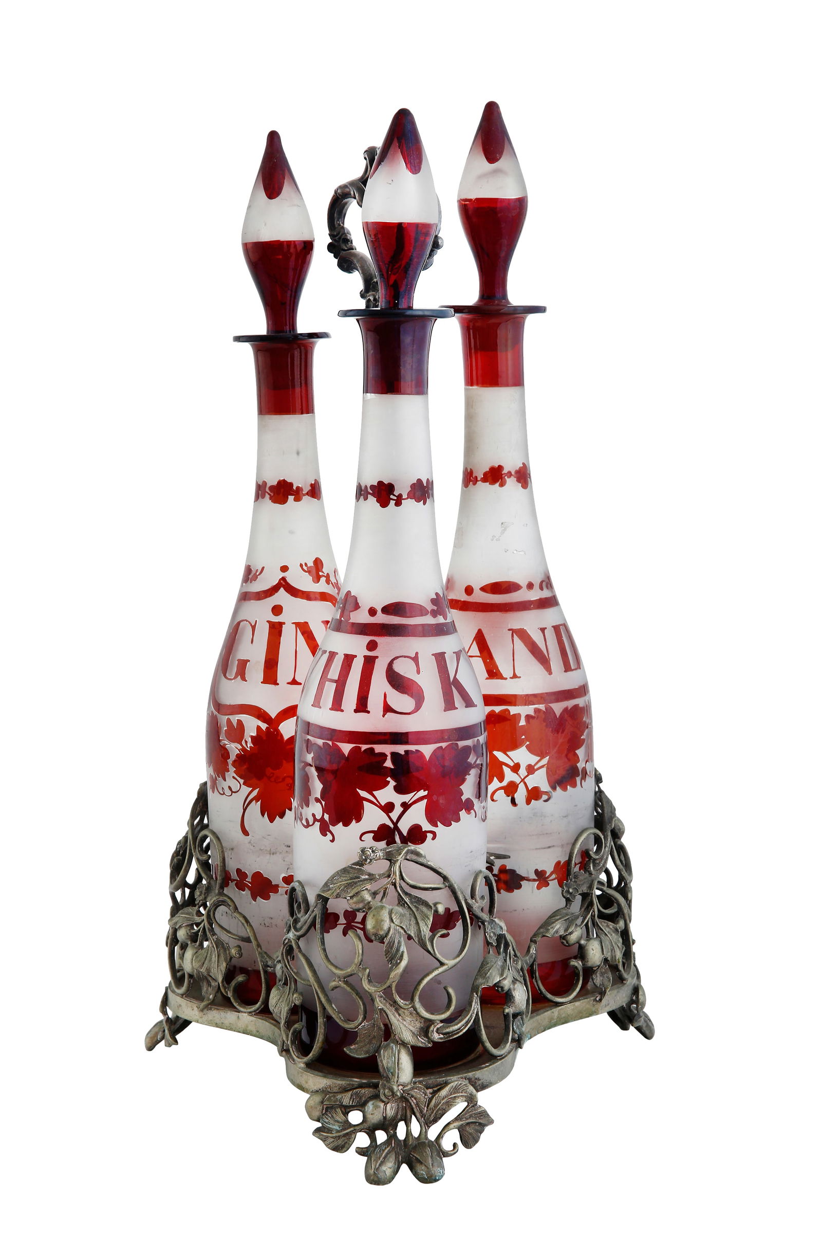 SET OF THREE ENGLISH DECANTERS: Early 20th century. Made of silver-plated metal (silver residue), decorated with fruits, flowers, and leaves, with three bottles for brandy, whisky, and gin in ruby red glass against a frosted glass