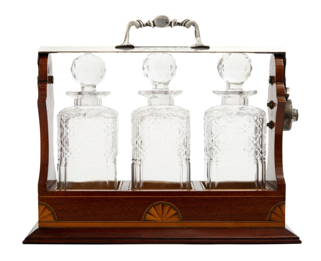 TANTALUS - ENGLISH DECANTER SET: Early 20th century, comprising three crystal decanters set in a wooden stand decorated with marquetry in a Fan Motif, and metal fittings. Width: 36 cm.