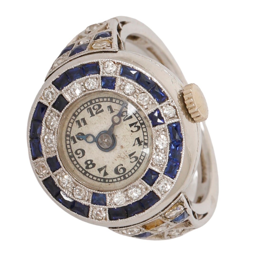 18K WHITE GOLD ART-DECO RING WATCH: Set with sapphires (one missing) and old-cut diamonds. Size approx. 5.5 US. This ring can be resized. Weight approx. 7 grams. The watch is not in working condition.
