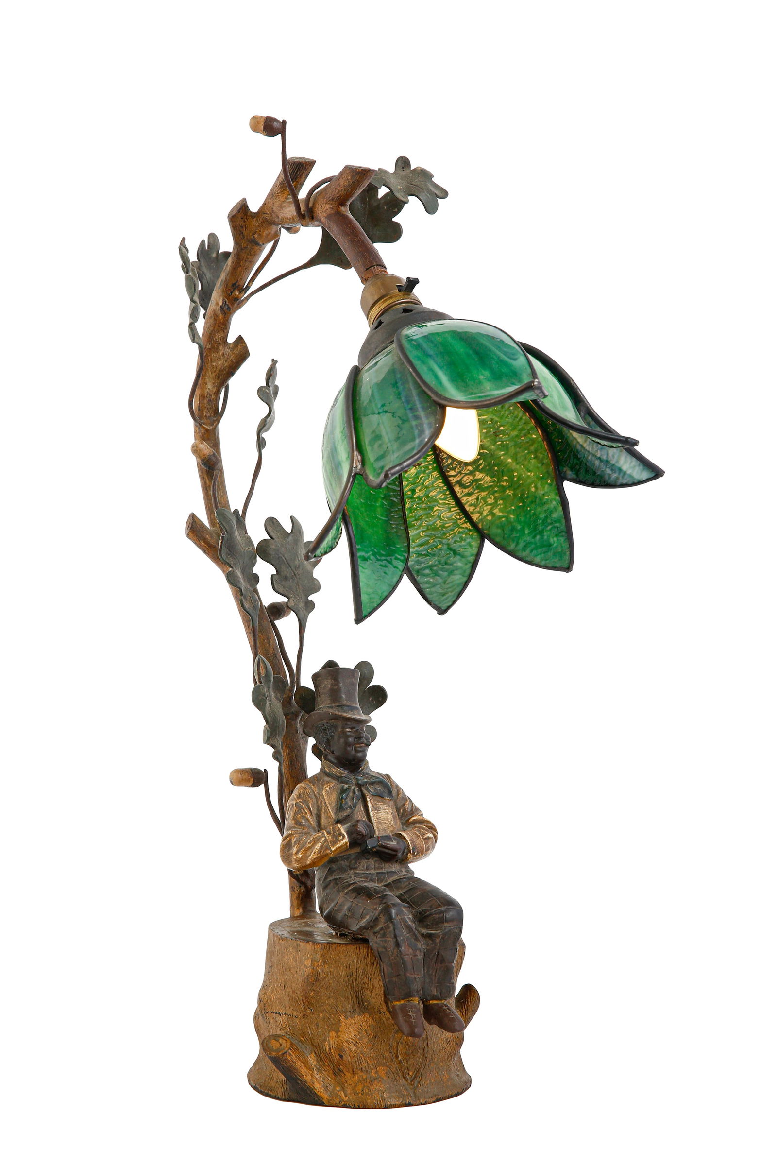JUGENDSTIL-STYLE TABLE LAMP: C. 1920, apparently Austrian. Made of metal, plaster, and glass. Sculpted in the form of a man wearing a hat, seated beneath a tree trunk, with a flower-shaped shade below. Decorated with cold-painted