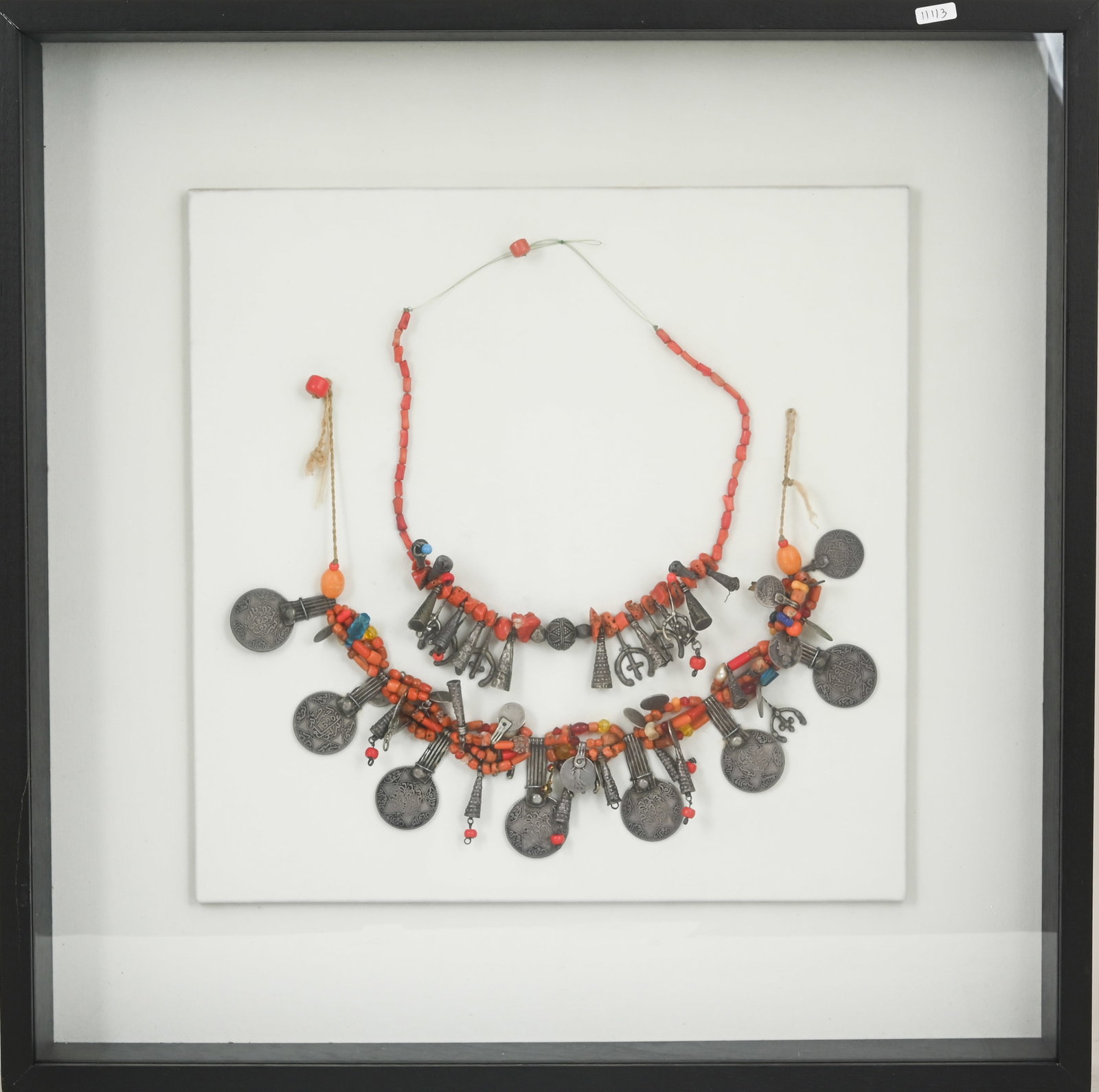 PAIR OF MOROCCAN BERBER PECTORAL ORNAMENTS: Tiznit, early 20th century. Large ornaments made of silver coinage, coral, mother-of-pearl, incense resin, and additional elements. Mounted in a framed display case. Frame dimensions: 52 ?— 52 cm.