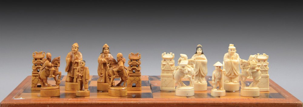 CHINESE IVORY CHESS SET: C. 1920. carved figurines inspired by the Chinese imperial court. white and brown pieces in different design. (white pawns with hats and spears, brown pawns with swards, white king with closed cloak,