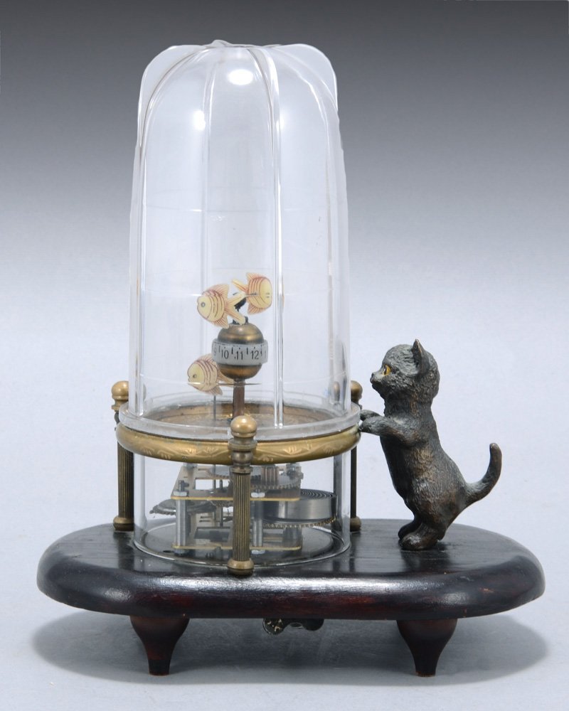 CURIOUSITY. CHINESE CLOCK SHAPED AS A CAT FOLLOWING: set hand, moving numerals. oval wood base, metal kitten. plastic cover. height: 22 cm. in working condition.