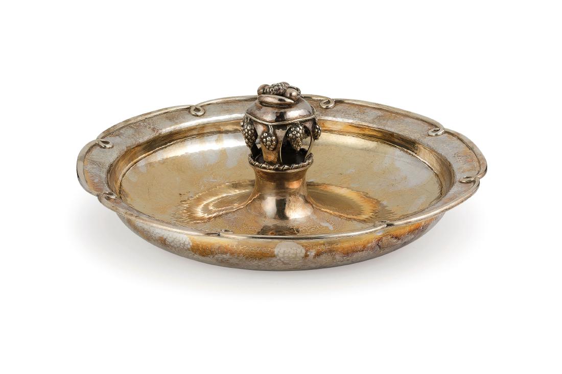 CENTROTAVOLA IN ARGENTO, LONDRA, 1933, ORAFO A.E. JONES: di forma circolare dal bordo sagomato, superficie martellata, presa centrale decorata a frutti- usure Alt. cm 12, diam. cm 30,5- peso gr 1018 A GEORGE V SILVER CENTREPIECE, LONDON, 1933, MARK OF A.E.