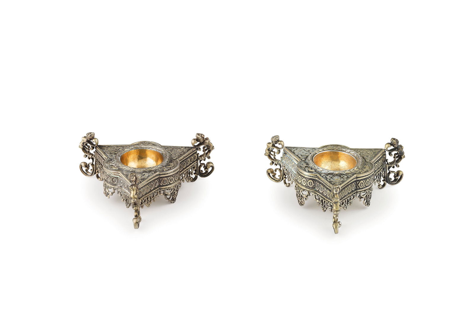 COPPIA DI SALIERE IN ARGENTO DORATO, HANAU, XIX-XX: a sezione triangolare, tre piedini a volute e antropomorfi, bordo traforato- usure Alt. cm 5, larg. cm 12-5 peso gr. 372 A PAIR OF GERMAN SILVER-GILT SALTCELLARS, HANAU. 19TH-20TH CENTURY- WEAR (2)