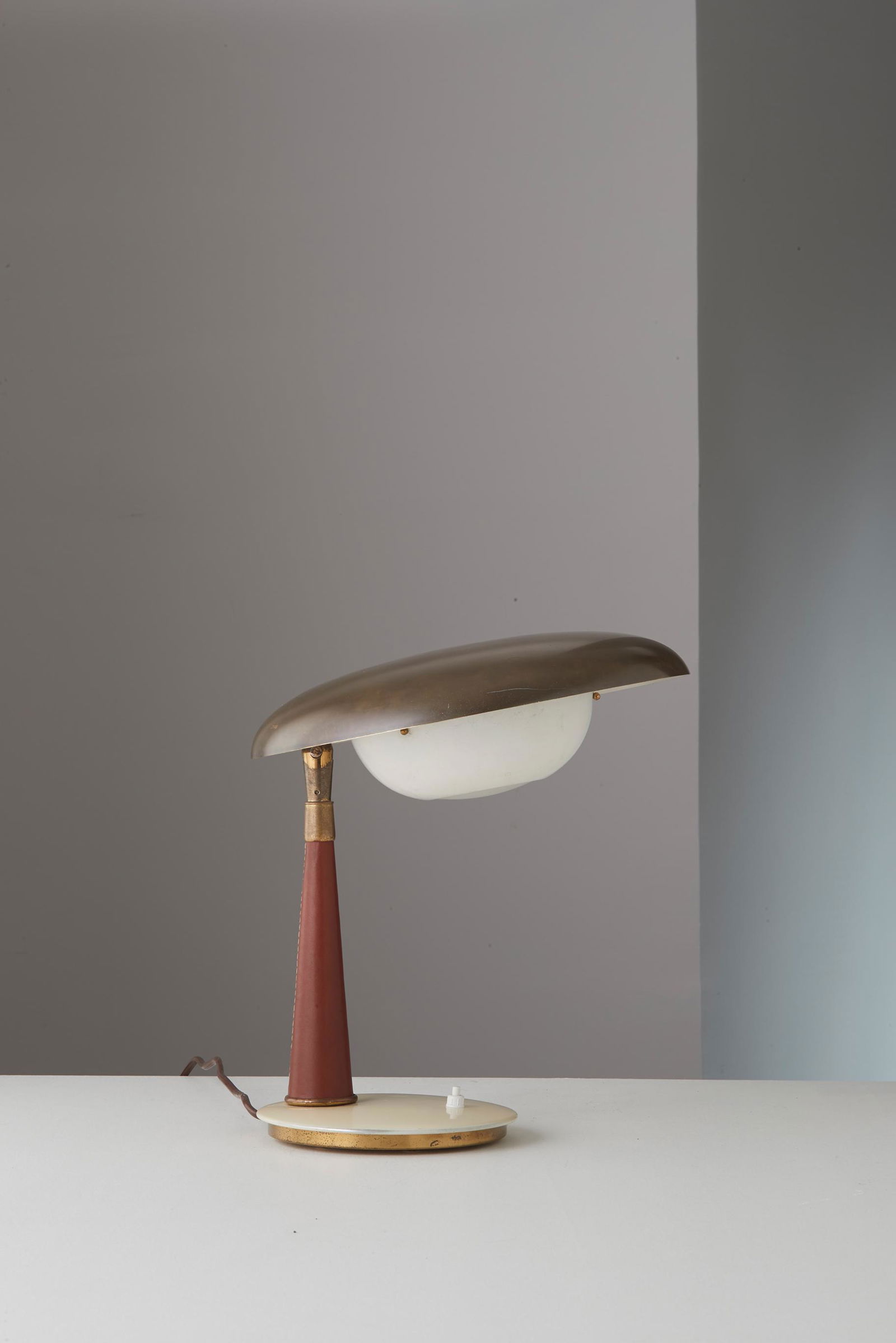 ANGELO LELII: Lampada da tavolo. Ottone, alluminio smaltato, vetro satinato, cuoio. Produzione Arredoluce anni '50. cm 30x35 Buone condizioni generali, piccole righe e trascurabili segni di usura. Lievi ossidazione