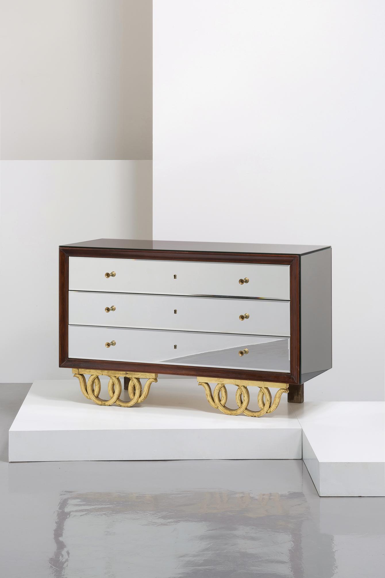 MANIFATTURA ITALIANA: Cassetiera. Legno, legno dorato, cristallo specchiato. Italia anni '50. cm 83x135x53 Discrete condizioni generali. Righe, graffi, mancanze alla vernice. Alcuni elementi da riconsolidare. QUITE GOOD GE