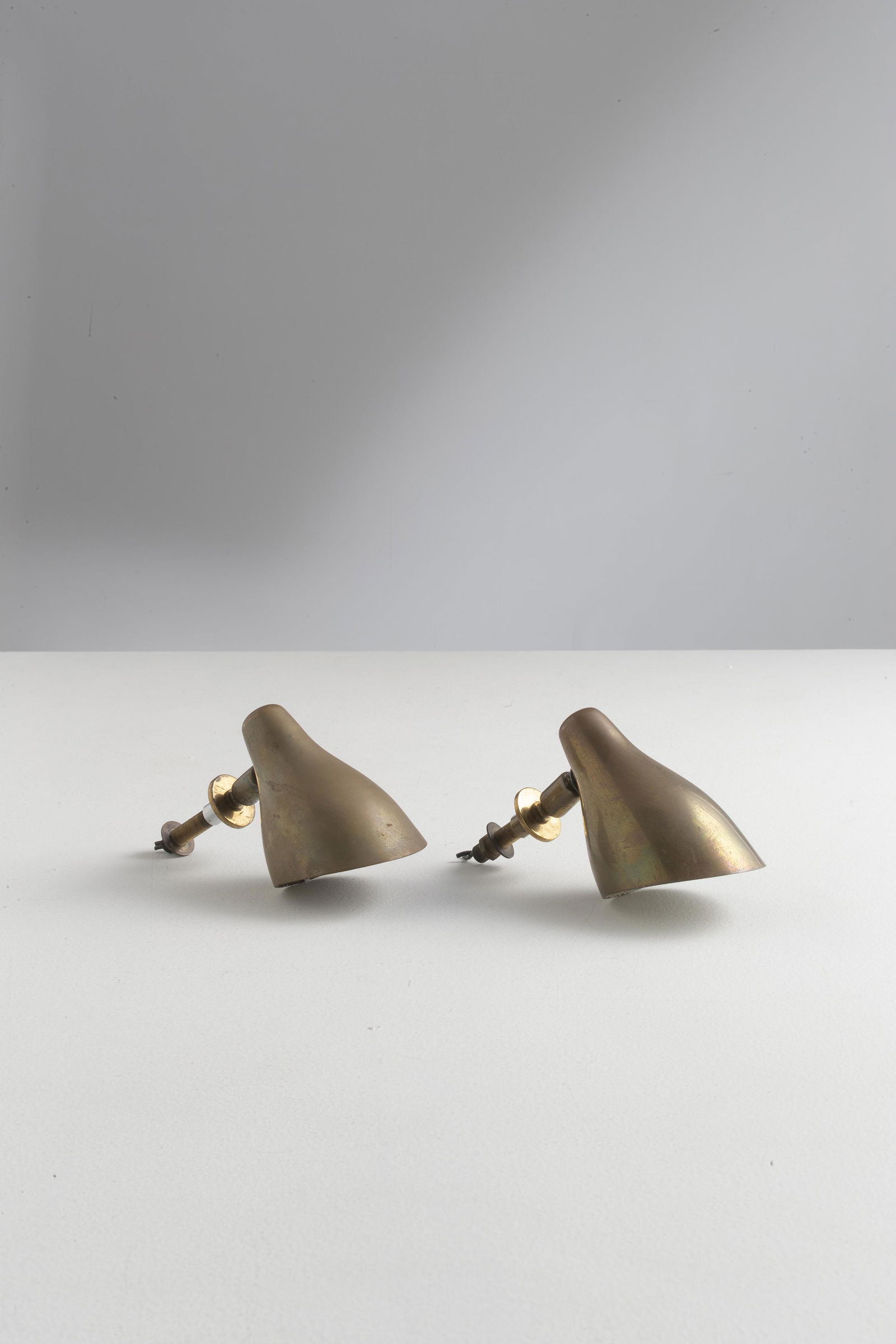 GIUSEPPE OSTUNI: Coppia di lampade da boiserie. Ottone. Produzione Oluce anni '50 ca. cm 15x8 A PAIR OF WALL LAMPS BY G. OSTUNI Normali Righe, leggeri graffi. Ottone in patina. Mancanze alla vernice nella parte intern
