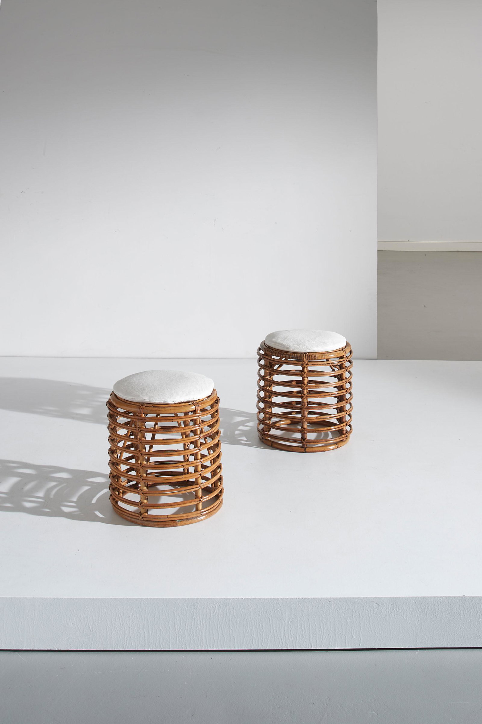 TITO AGNOLI: Coppia di sgabelli. Canna d'India, midollino intrecciato, tessuto imbottito. Italia anni '50. cm 40,5x37 A PAIR OF STOOLS BY T. AGNOLI