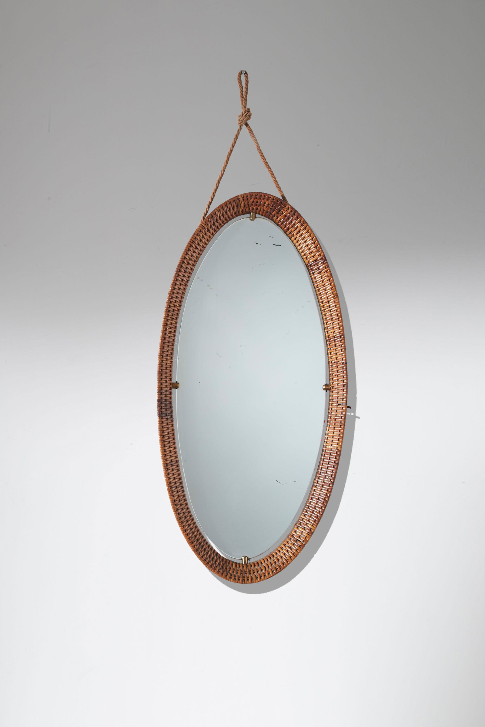 MANIFATTURA ITALIANA: Specchio. Canna d'India trafilata, ottone, vetro specchiato, corda di canapa. Italia anni '60. cm 89x45x5 AN ITALIAN MIRROR Buone condizioni. Piccole mancanze di canna d'India. Righe, graffi.